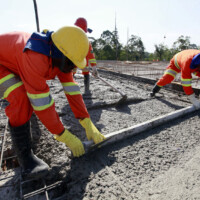 workers pouring cement in road construction on brazil